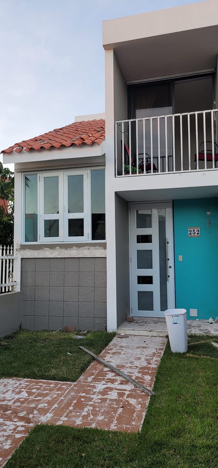 Fachada de dos plantas con ventanas y barandales de aluminio